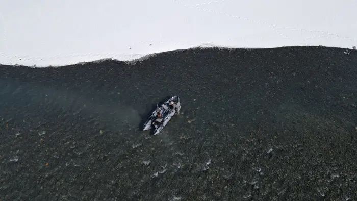 Raft on dark water beside a snowy bank